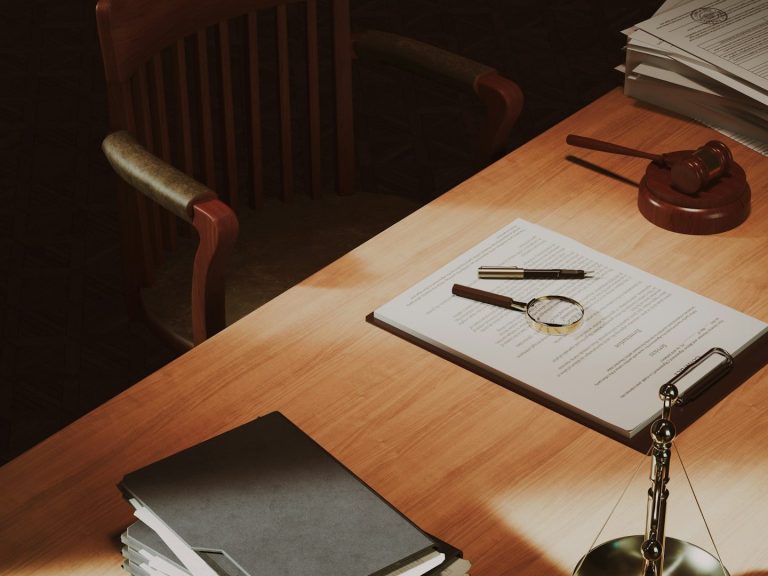 Mesa de trabajo con documentos, lupa, bolígrafos y una lámpara. Sillas en el fondo.
