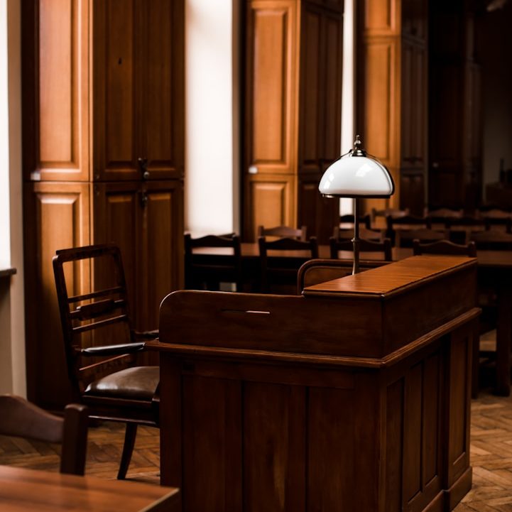 Interior de una sala de juicios, con muebles de madera y una lámpara de escritorio.
