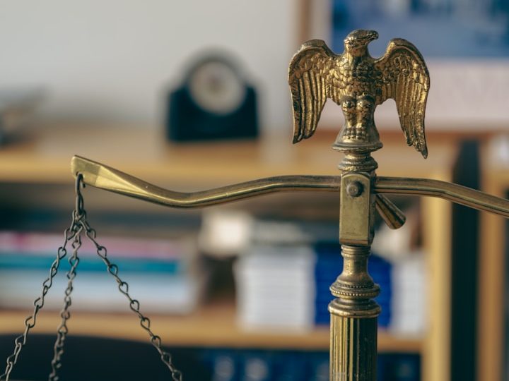Símbolo de un águila sobre una balanza, representando la justicia. Fondo desenfocado.